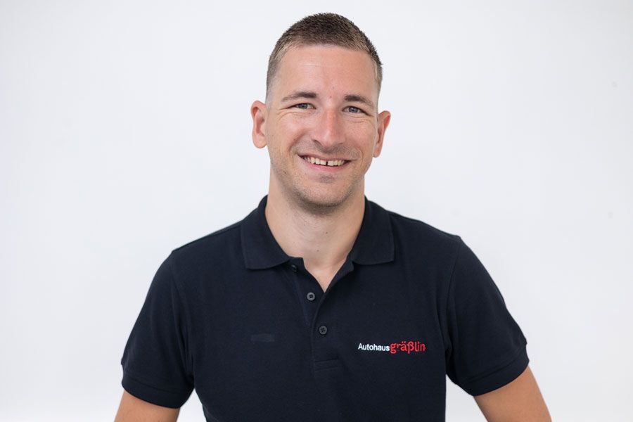 Ein Mann in einem schwarzen Poloshirt lächelt in die Kamera.