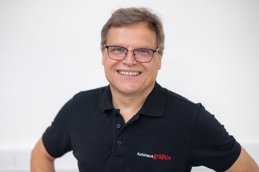 Ein Mann mit Brille und schwarzem Hemd lächelt in die Kamera.