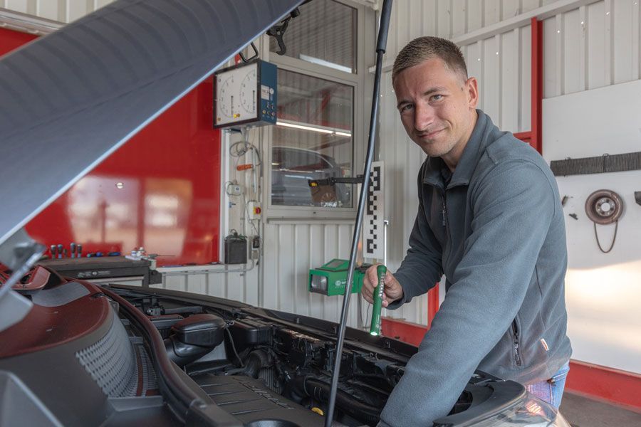Ein Mann arbeitet in einer Garage am Motor eines Autos.