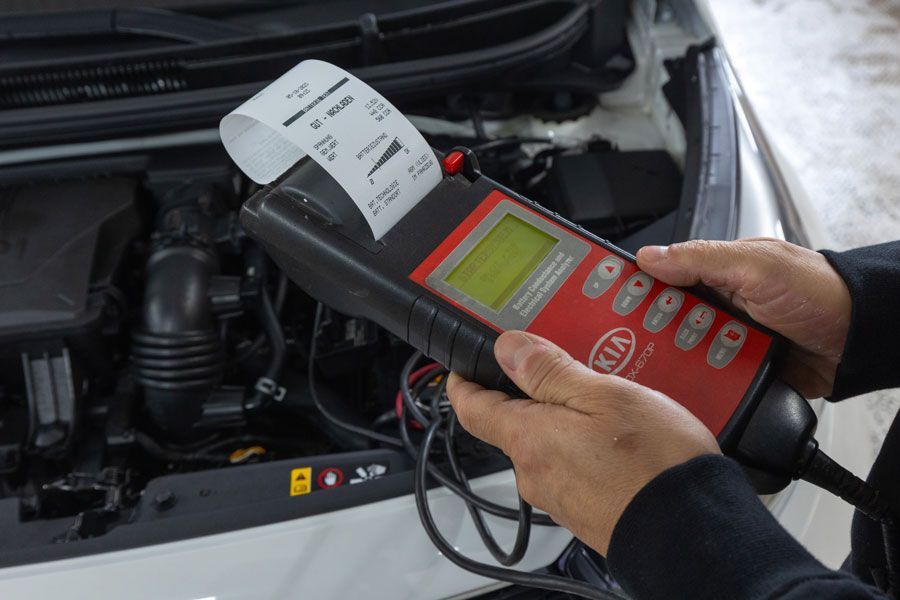 Mechaniker verwendet einen Kia-Batterietester in der Nähe eines Automotors.