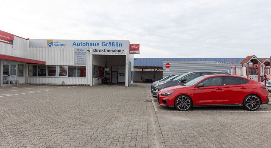 Ein rotes Auto steht vor einem Autohaus.