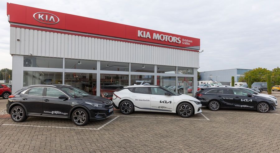 Außenansicht eines vom Autohaus Grässlin mit drei geparkten Kia-Fahrzeugen.