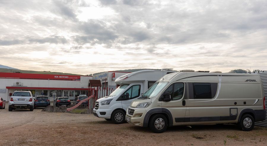 Eine Reihe von Wohnmobilen, die vor einem Gebäude geparkt sind.