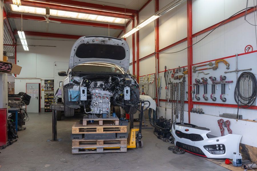 In einer Garage wird mit geöffneter Motorhaube ein Auto gebaut.