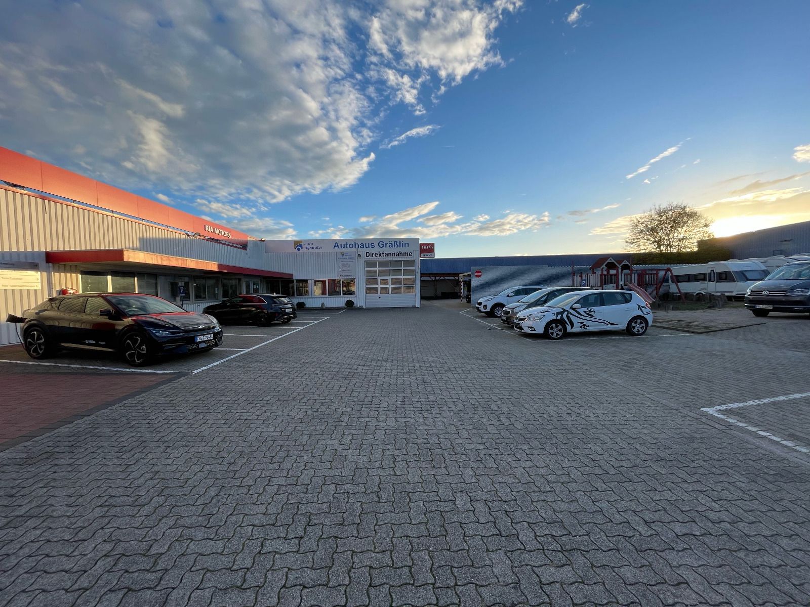 Auf einem Parkplatz vor einem Gebäude steht eine Reihe von Autos.