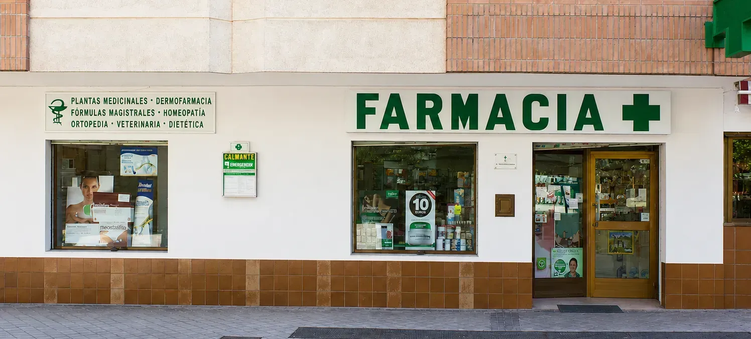 Fachada de una farmacia con letrero verde que dice