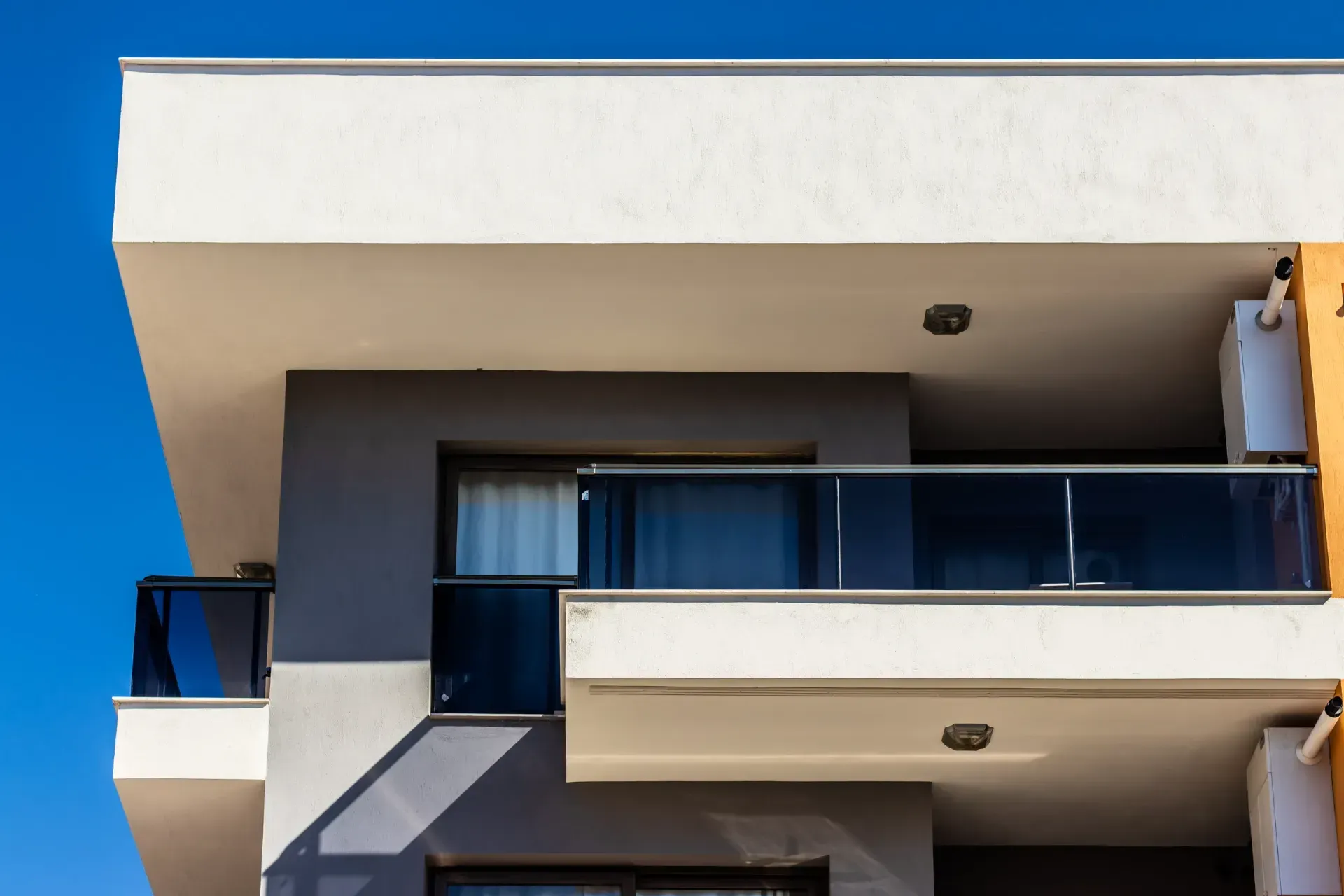 Un moderno edificio de apartamentos con balcón y un cielo azul al fondo.