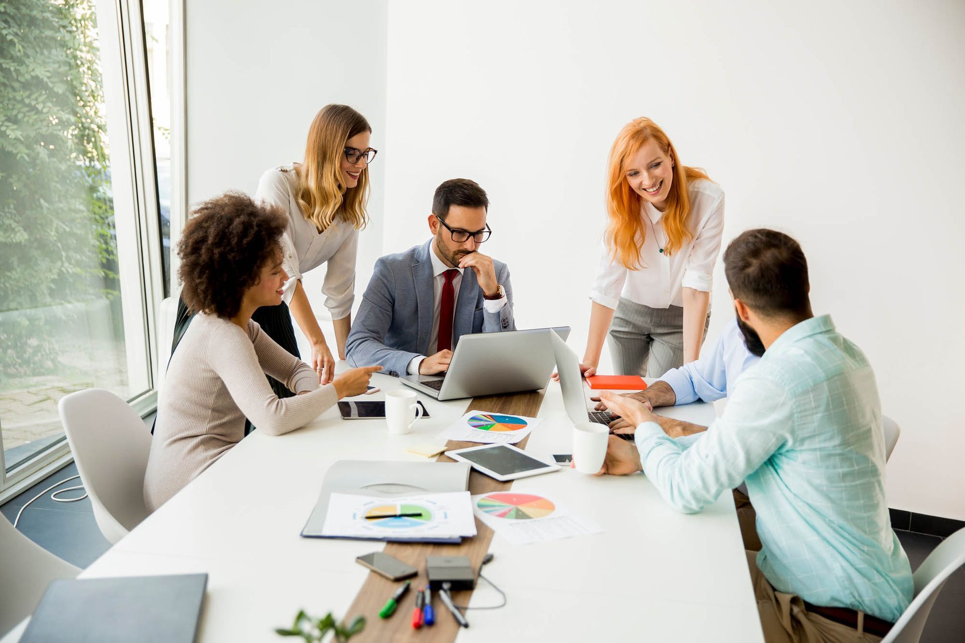 Eine Gruppe von Leuten sitzt mit Laptops um einen Tisch herum.