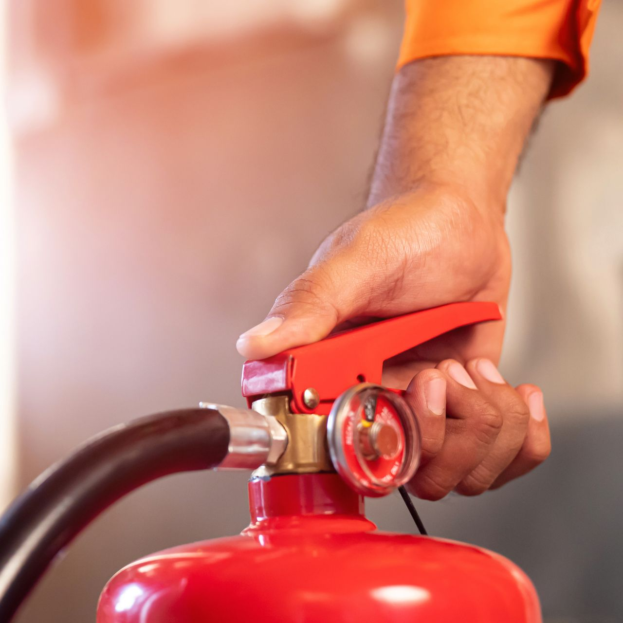 Une personne tient un extincteur rouge, prêt à l'emploi.