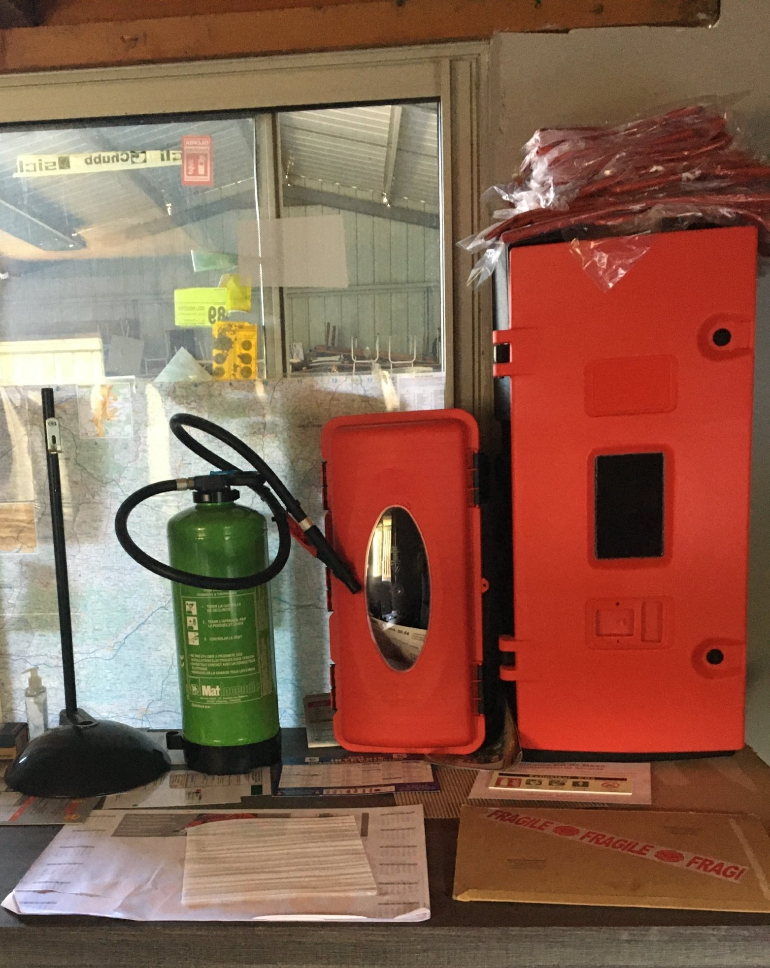 Extincteur, boîtes d'urgence et documents sur une table devant une fenêtre.