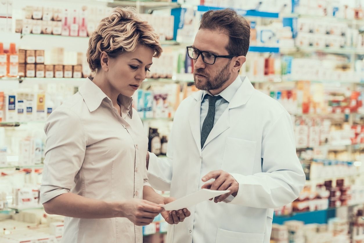 Un farmacéutico está hablando con una mujer en una farmacia.