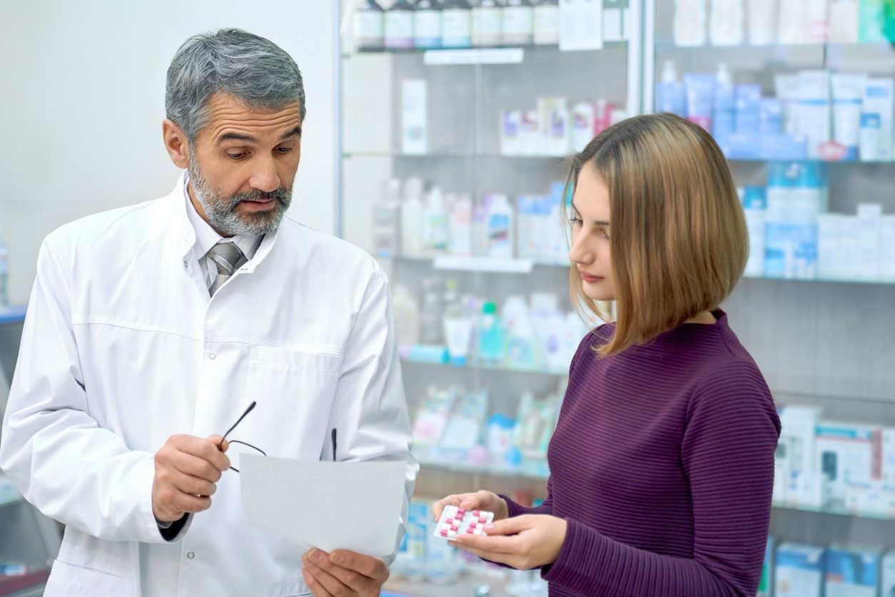 Un farmacéutico está hablando con una mujer en una farmacia.