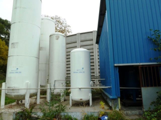 Un edificio azul con muchos tanques delante.