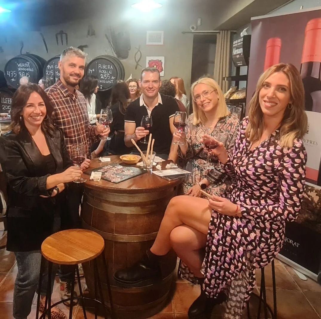 Cinco personas se reunieron alrededor de una mesa hecha con un barril de vino de madera, sonriendo