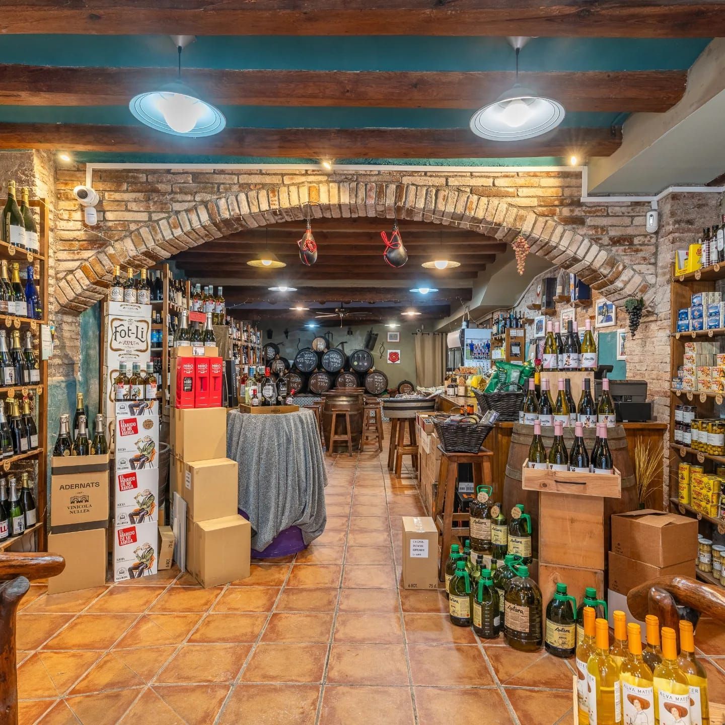 Interior de una vinoteca rústica con arcos de ladrillo visto, vigas de madera, suelos de baldosas 