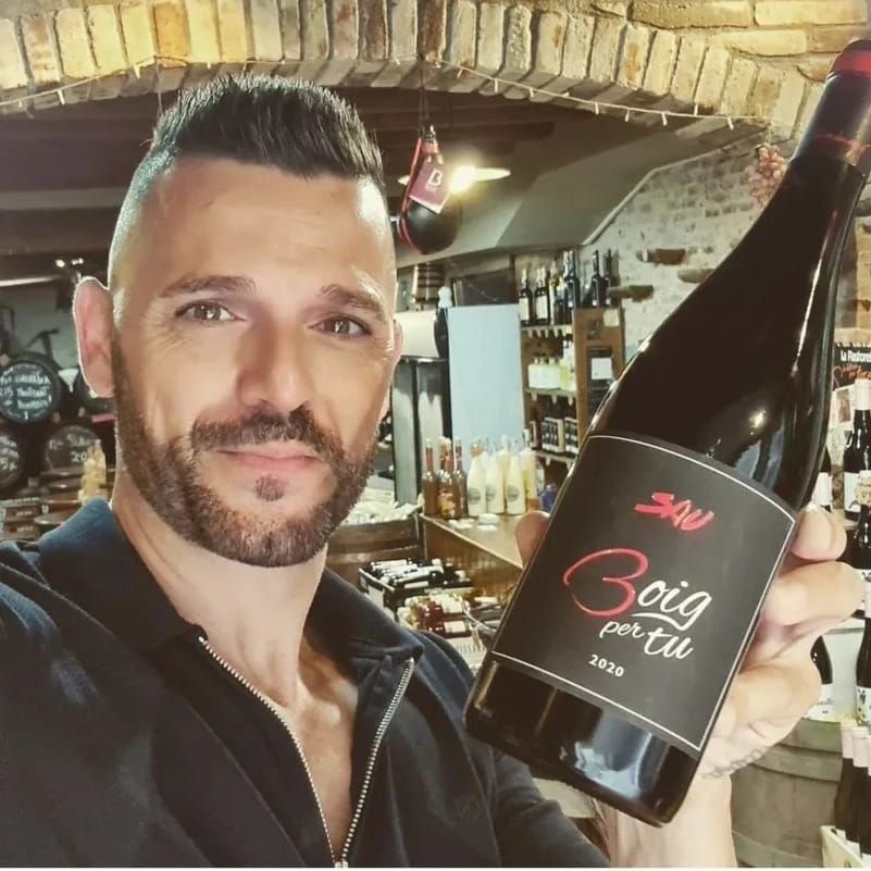 Una persona sostiene una botella de vino tinto 