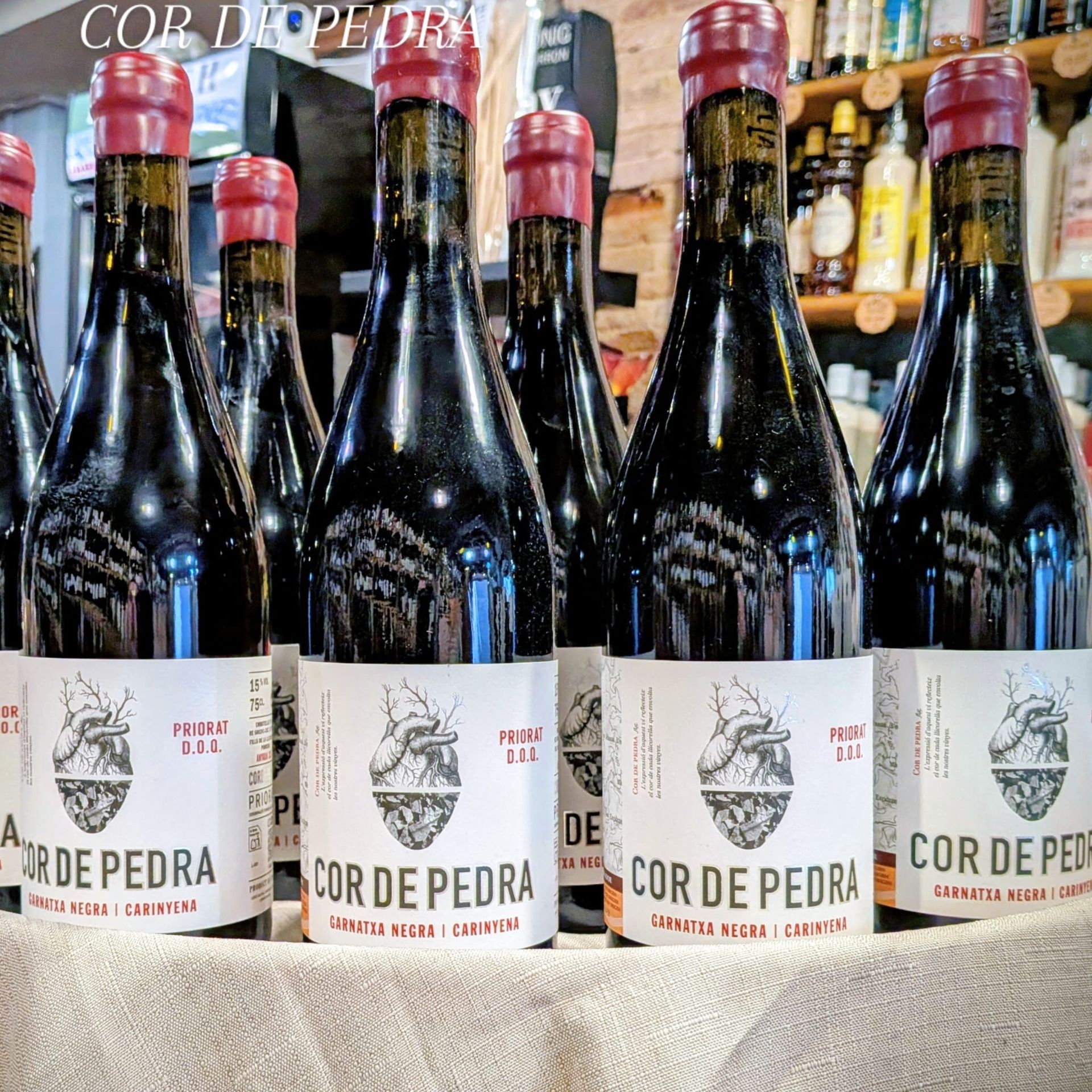 En la estantería de una tienda se exhiben varias botellas de vino Cor de Pedra con etiquetas