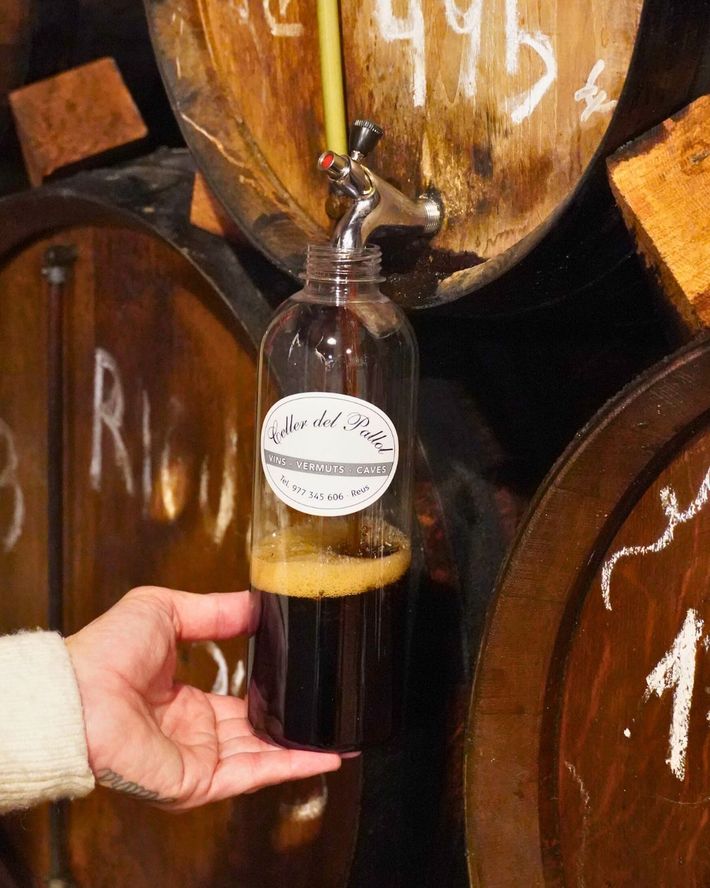 Una mano sostiene una botella de plástico que se está llenando con vino tinto