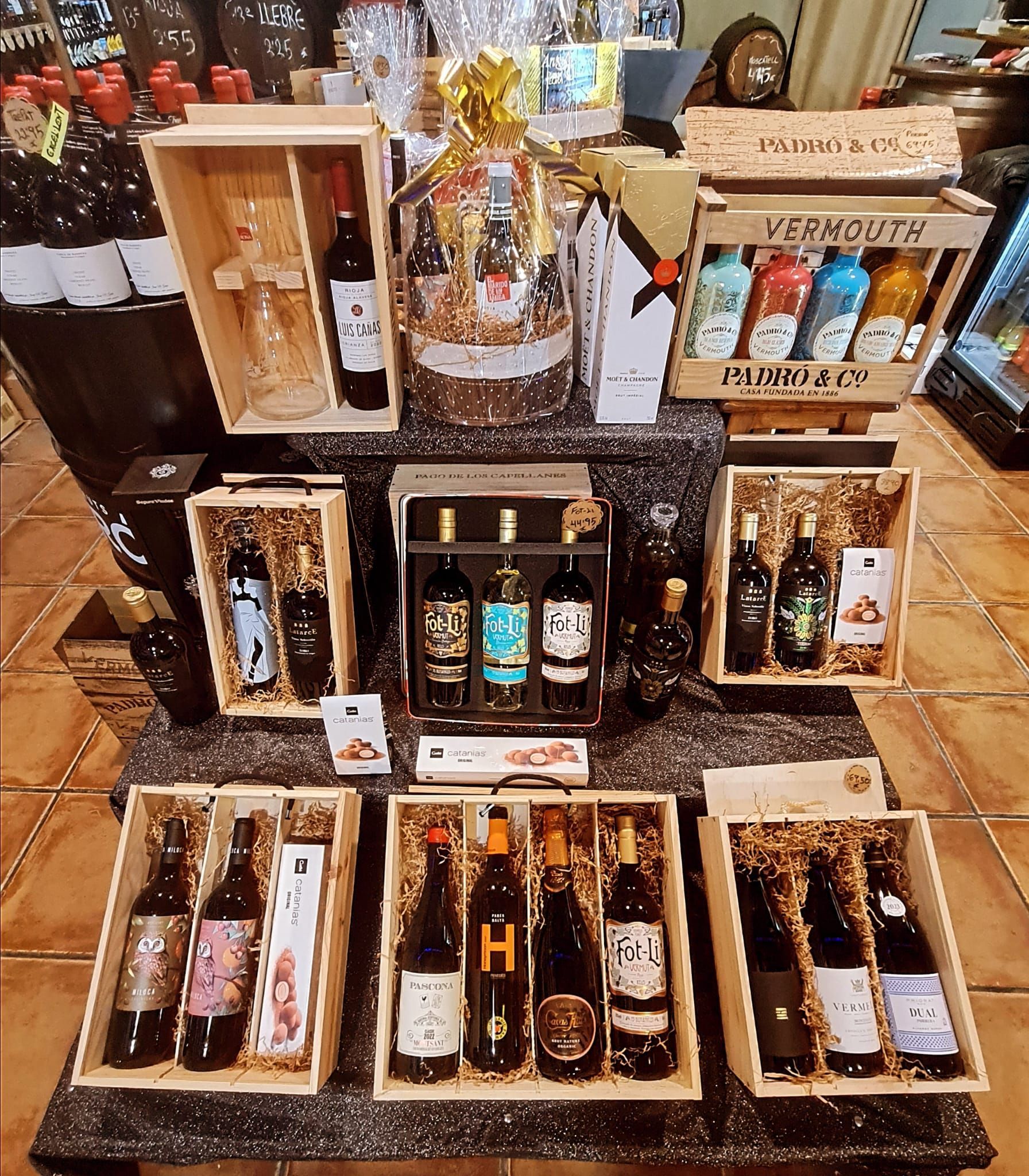 Una vitrina con una selección de vinos embotellados y vermuts variados, empaquetados en cajas de madera