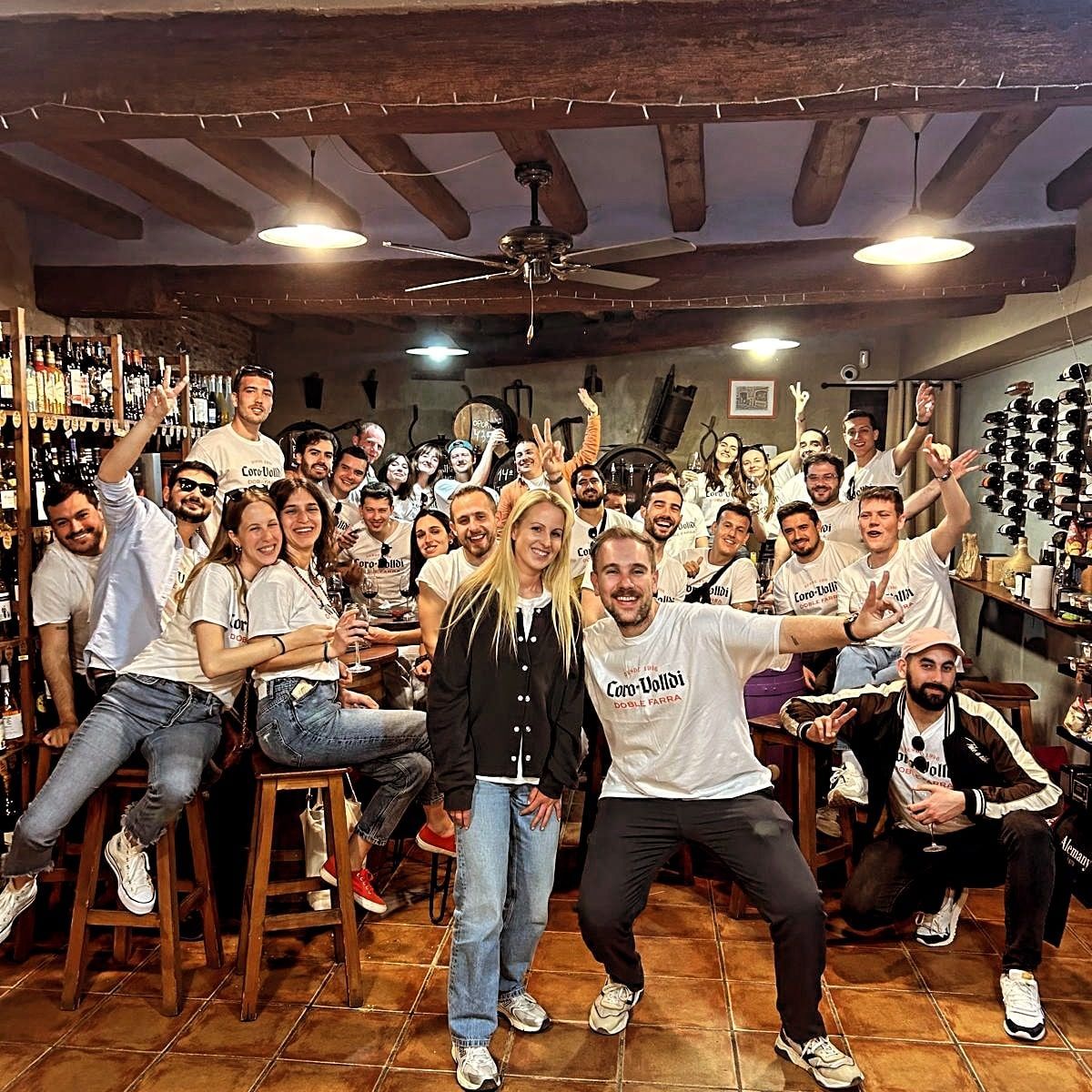 Un numeroso grupo de personas sonríe y posa en una habitación rústica con vigas de madera