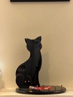 Plaque funéraire en forme de chat sur une base ronde, avec crochets.