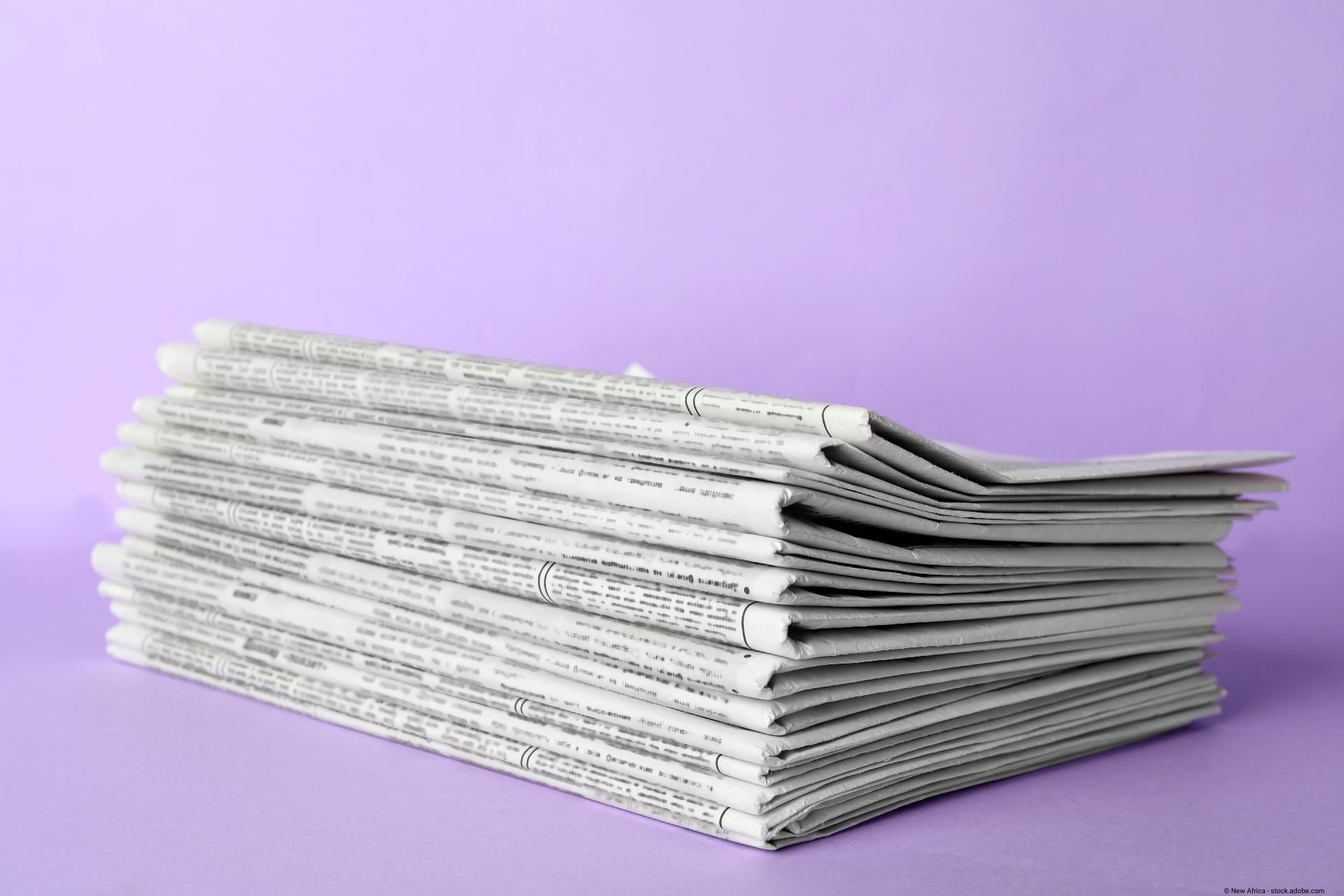 Ein Stapel mit Zeitungen auf lilafarbenem Hintergrund