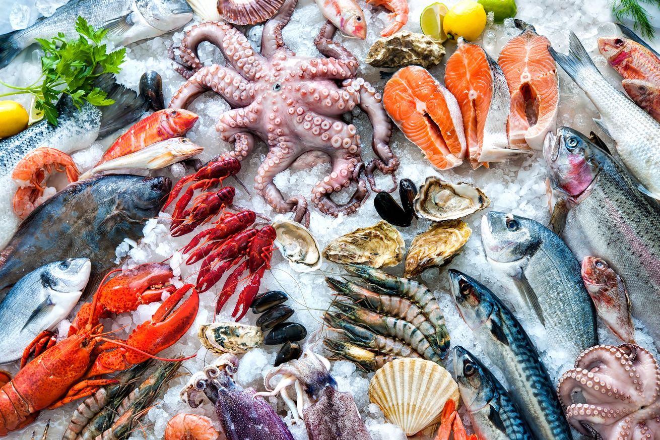 Assortiment de fruits de mer frais sur glace pilée, comprenant poisson, crevettes, poulpe, crabe et coquillages.