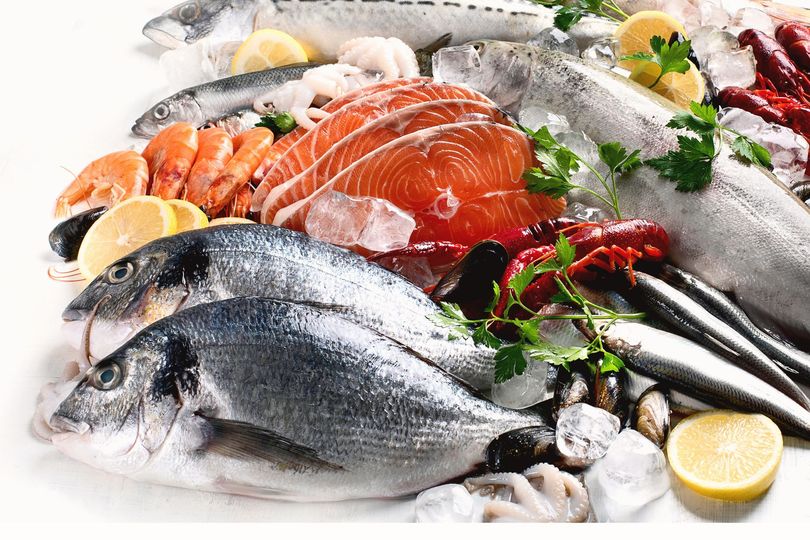 Assortiment de fruits de mer frais avec poisson, saumon, crevettes, citrons et glace présentés sur un présentoir