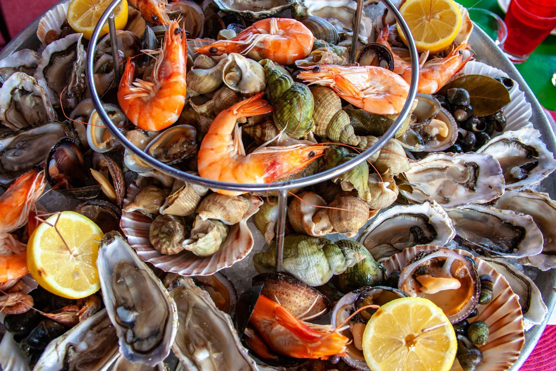Plateau de fruits de mer avec crevettes, palourdes, huîtres et quartiers de citron sur un plateau de service.