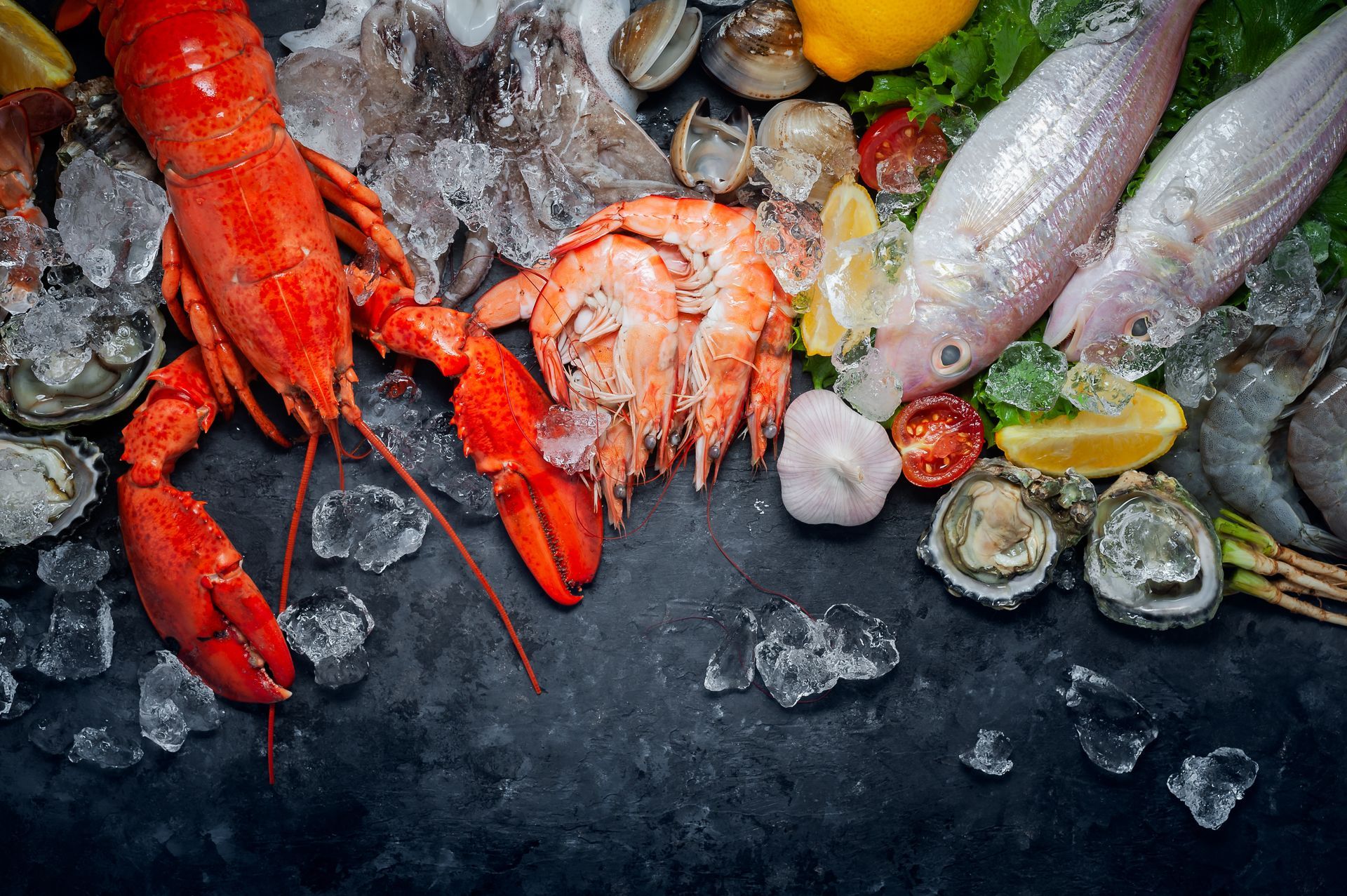 Assortiment de fruits de mer sur glace, comprenant des homards rouges, du crabe, des huîtres et des quartiers de citron.
