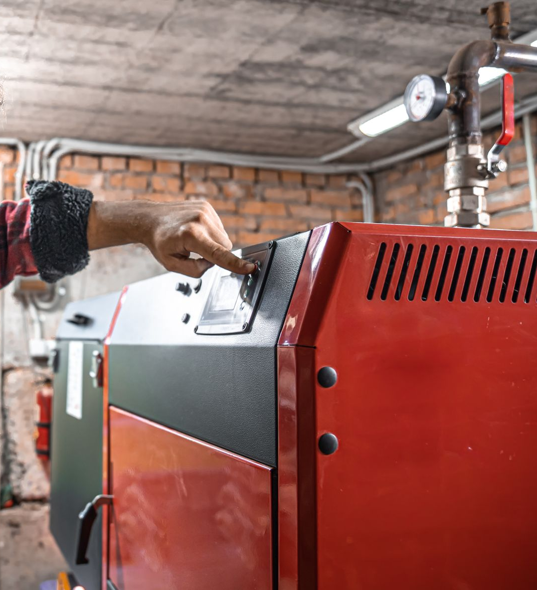La main d'une personne appuie sur un bouton d'une chaudière à fioul.