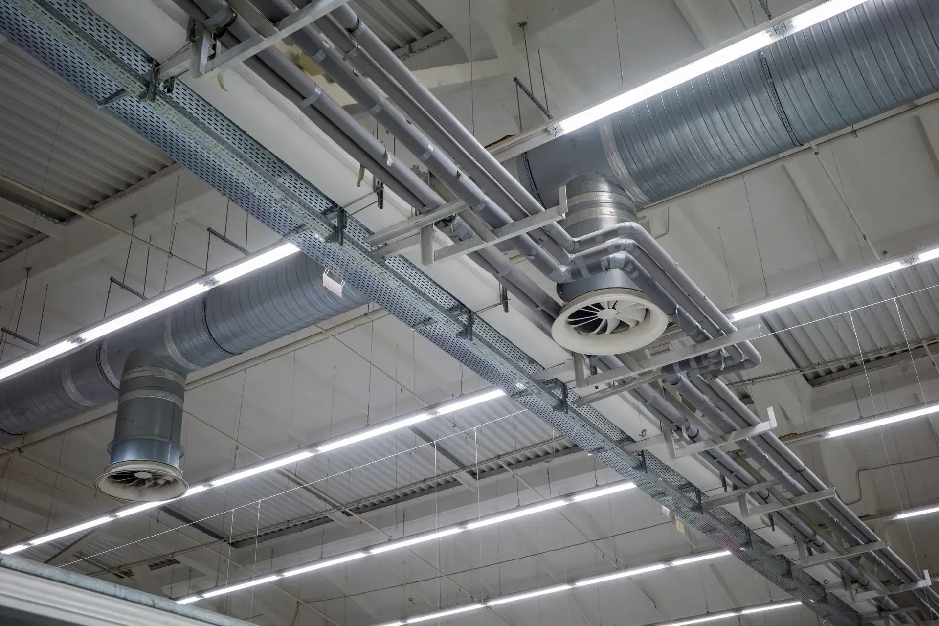 Système de VMC dans un bâtiment industriel, avec conduits et plafonniers.