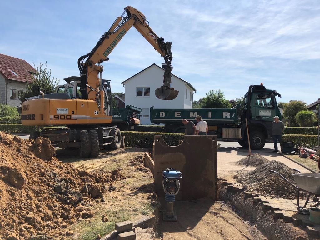 Ein gelber Bagger lädt Erde in einen Muldenkipper