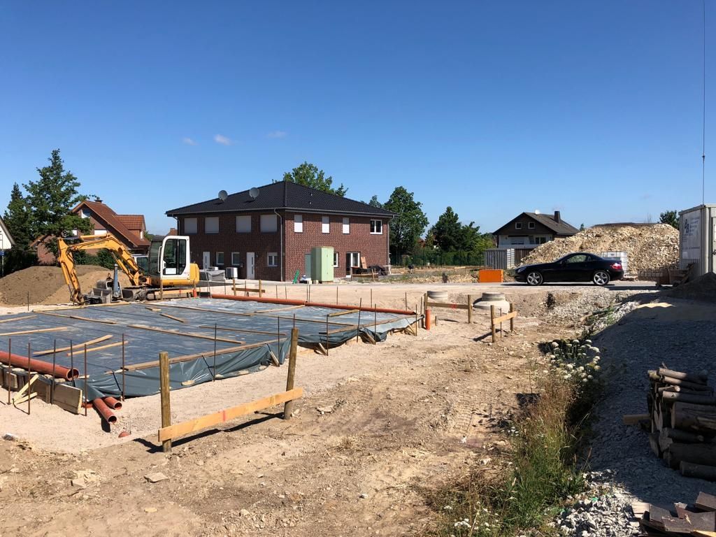 Eine Baustelle mit einem Haus im Hintergrund und einem davor geparkten Auto.