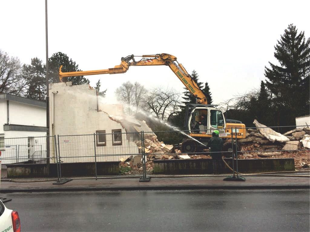 Ein großer gelber Bagger zerstört ein Gebäude
