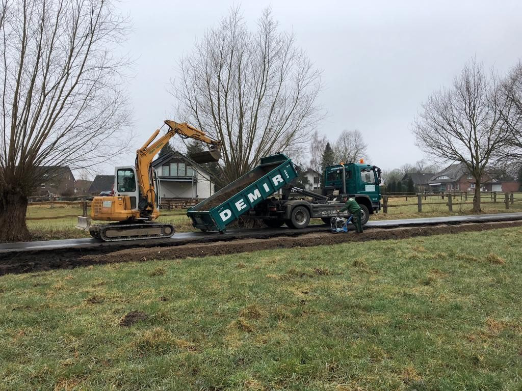 Ein Muldenkipper wird auf einem Feld von einem Bagger gezogen.