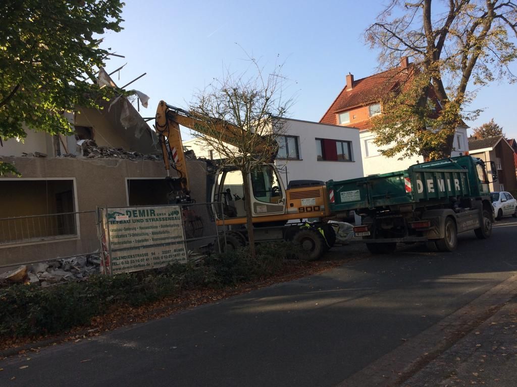 Vor einem Gebäude, das abgerissen wird, parkt ein Muldenkipper.