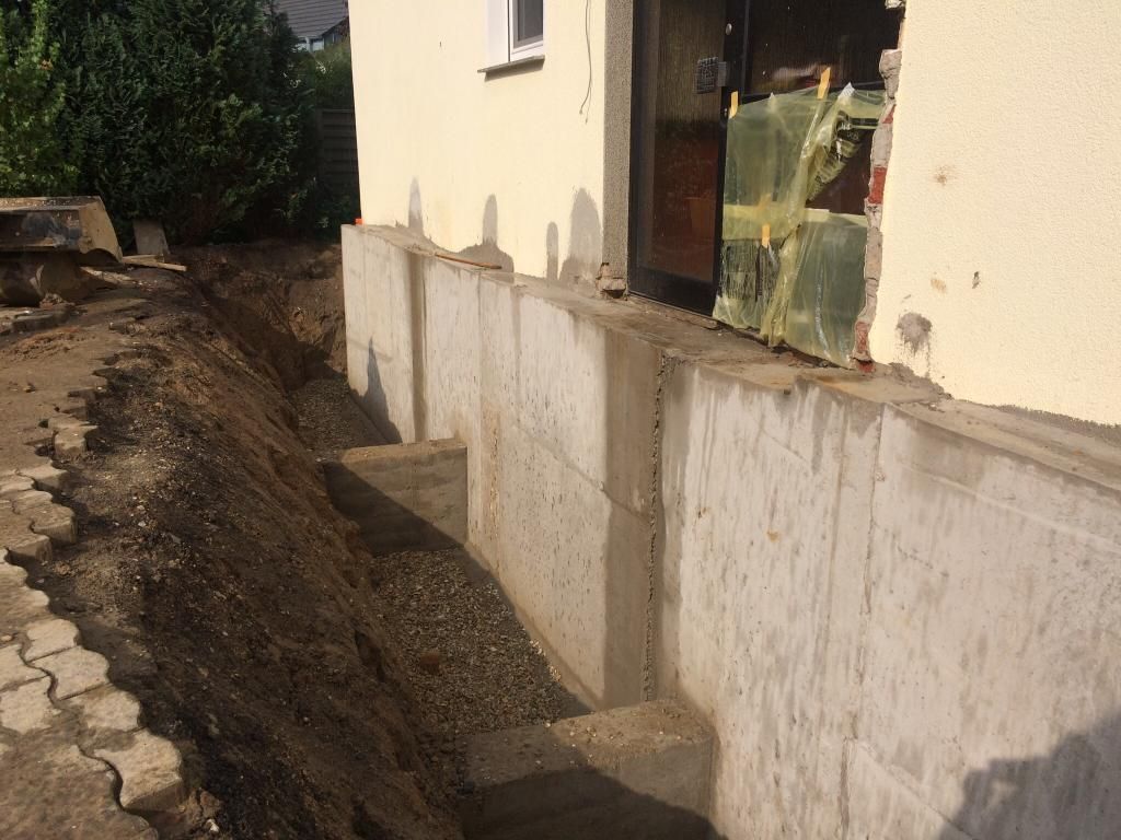 An der Seite eines Hauses wird eine Betonmauer gebaut.