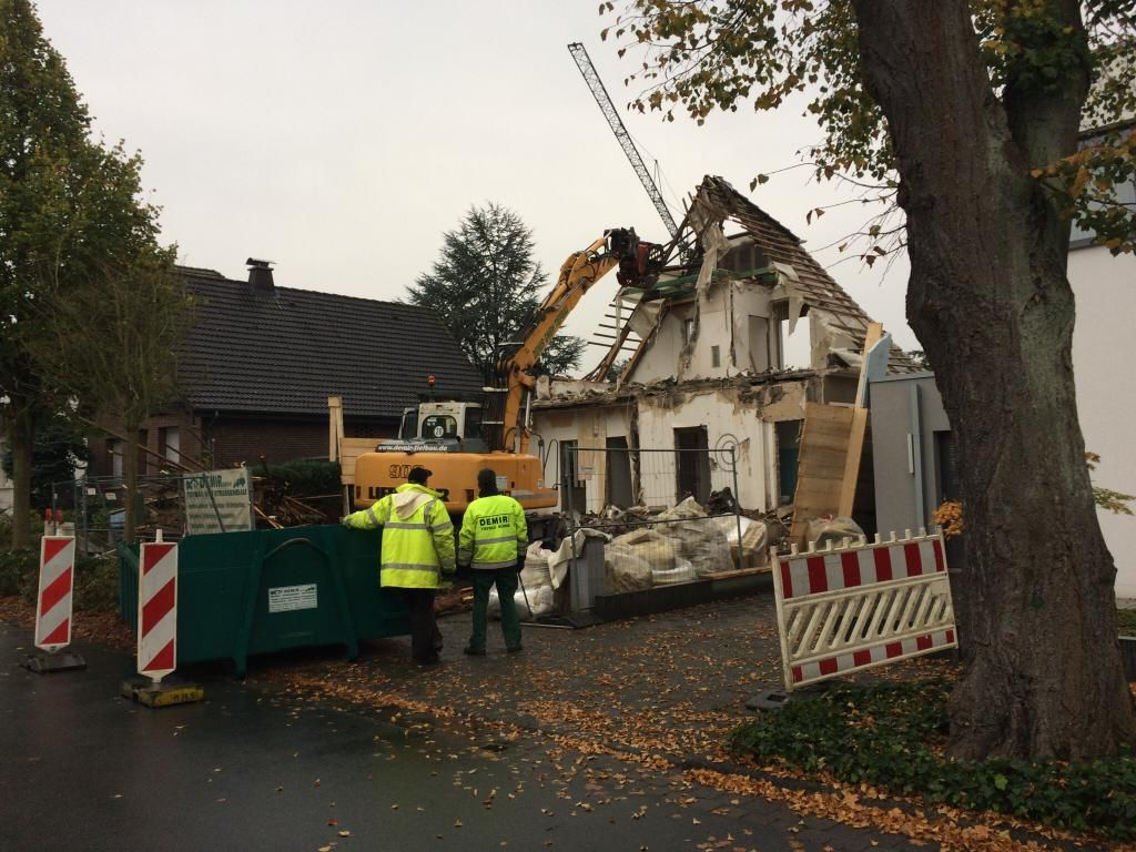Eine Gruppe Bauarbeiter steht vor einem abgerissenen Haus.