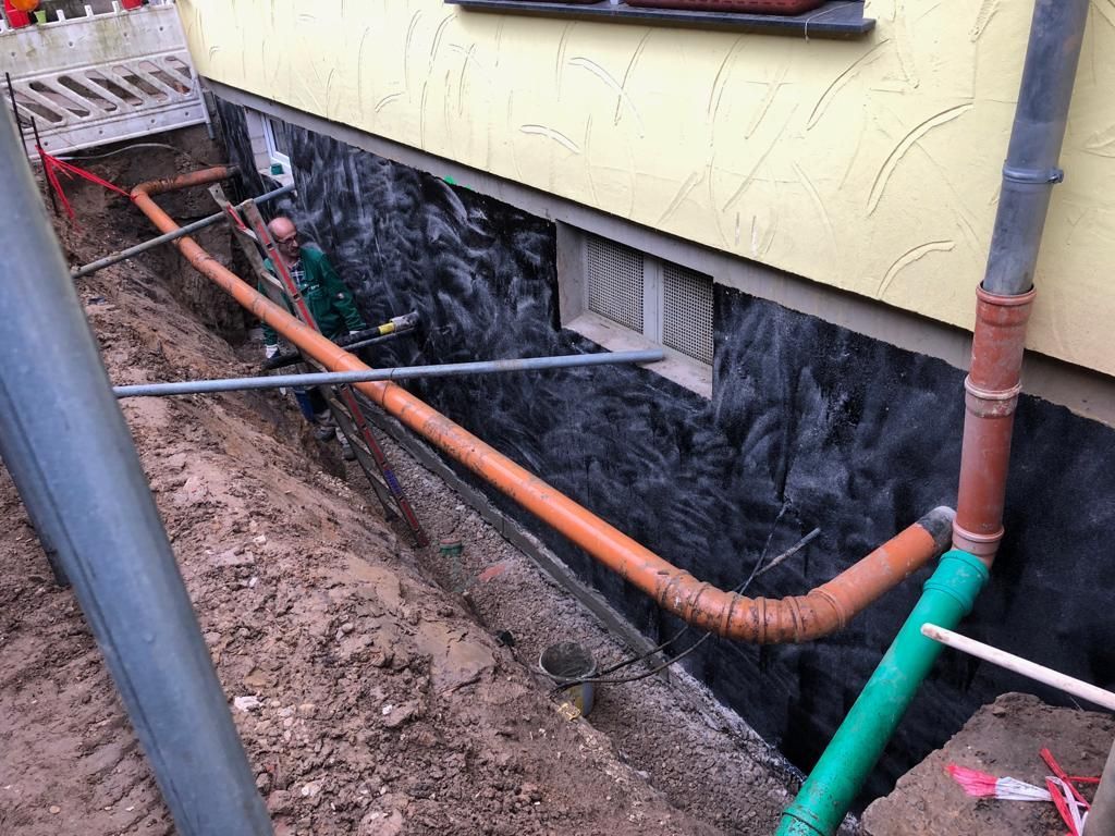 An der Seite eines Gebäudes wird ein Abflussrohr installiert.