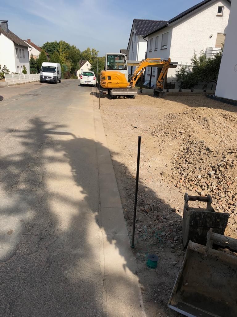 Am Straßenrand parkt ein gelber Bagger.