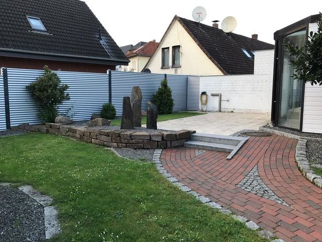 Ein gemauerter Gehweg führt zu einem Haus mit einer Satellitenschüssel auf dem Dach