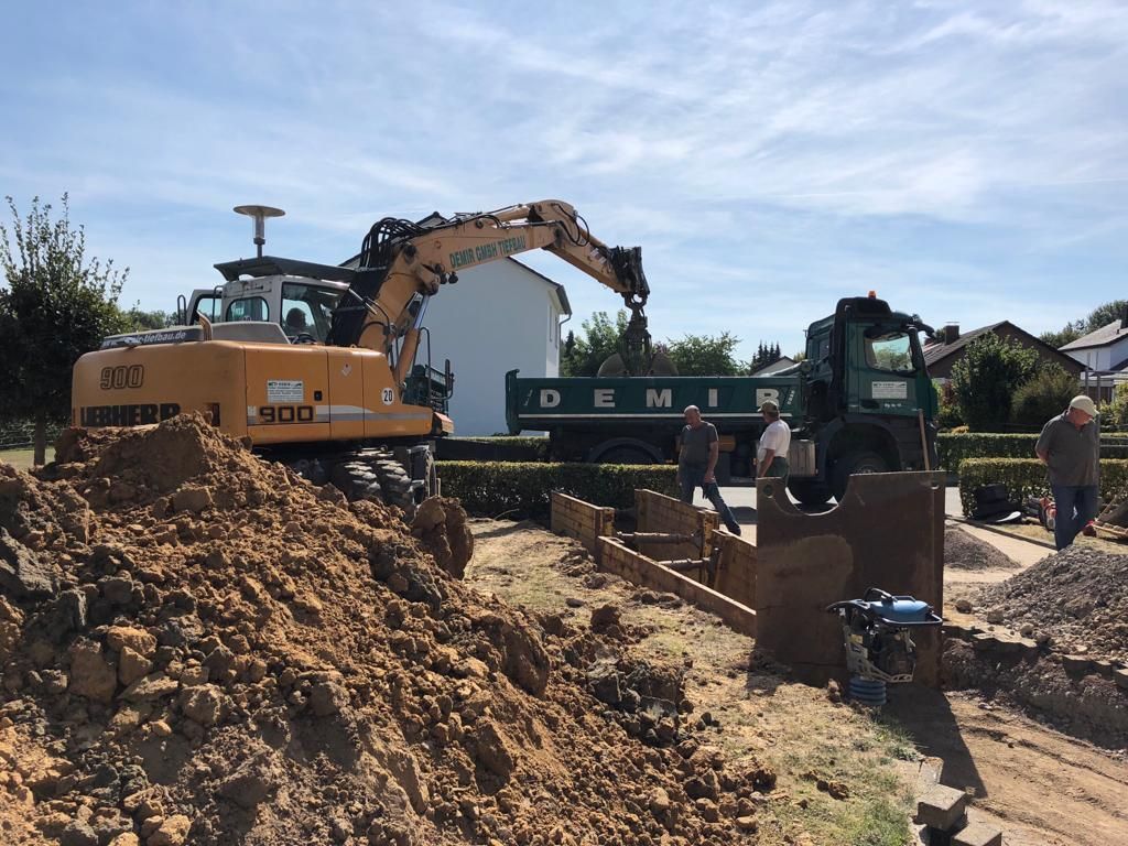 Ein großer Bagger lädt Erde in einen Muldenkipper.