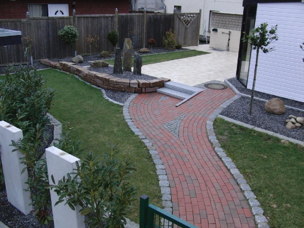 Ein Ziegelweg durch einen üppigen grünen Hof