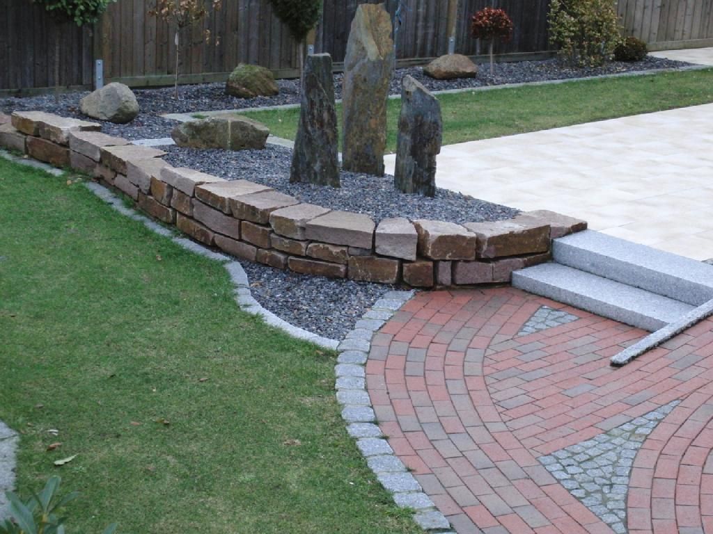 Ein gemauerter Gehweg in einem Garten mit einer Steinmauer