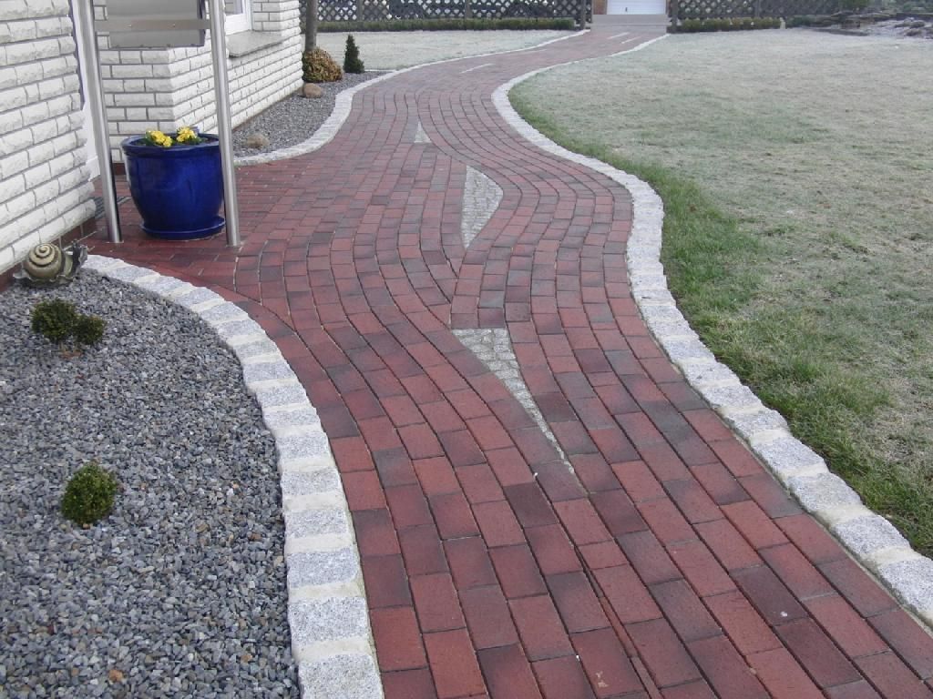 Ein Ziegelweg mit einem blauen Blumentopf an der Seite