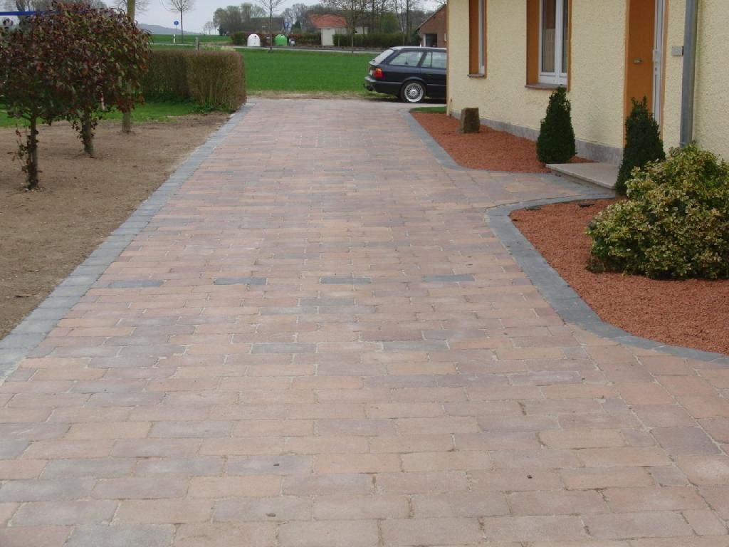 Eine gemauerte Auffahrt, die zu einem gelben Haus führt