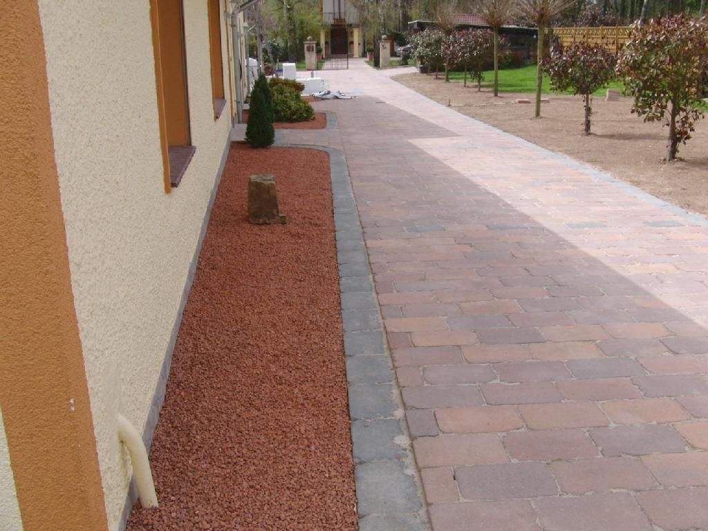 Ein gemauerter Gehweg, der zu einem Haus mit Bäumen im Hintergrund führt