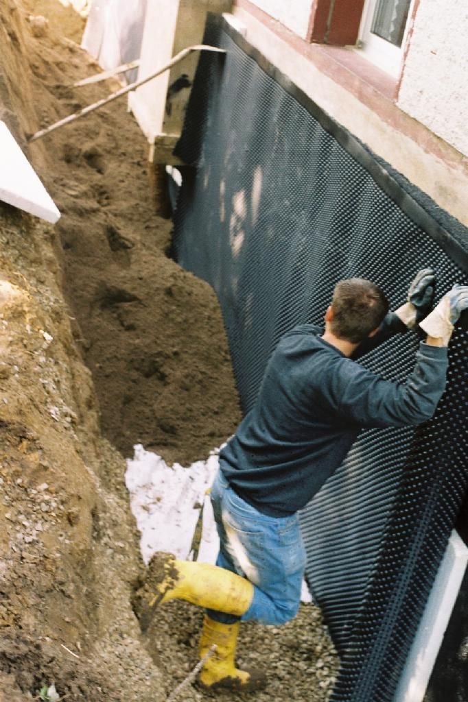 Ein Mann in gelben Stiefeln arbeitet an einer Mauer.