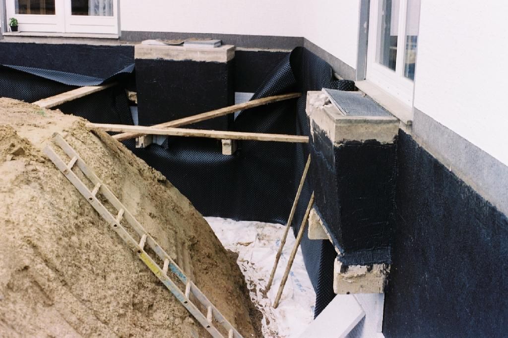 Eine Leiter steht auf einem Erdhaufen vor einem Gebäude